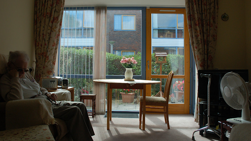 Resident sitting indoor at Extra care home, reading